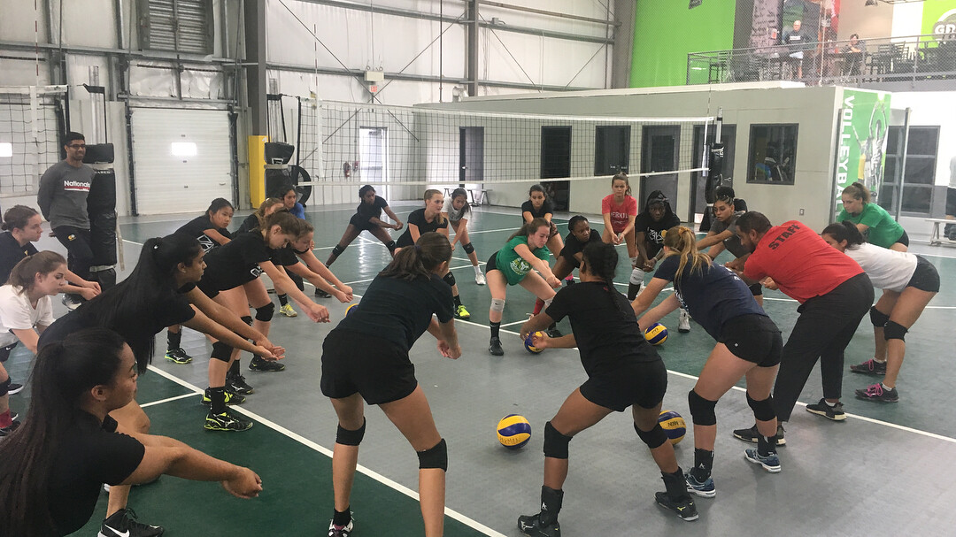 Girls volleyball players practicing with their coach